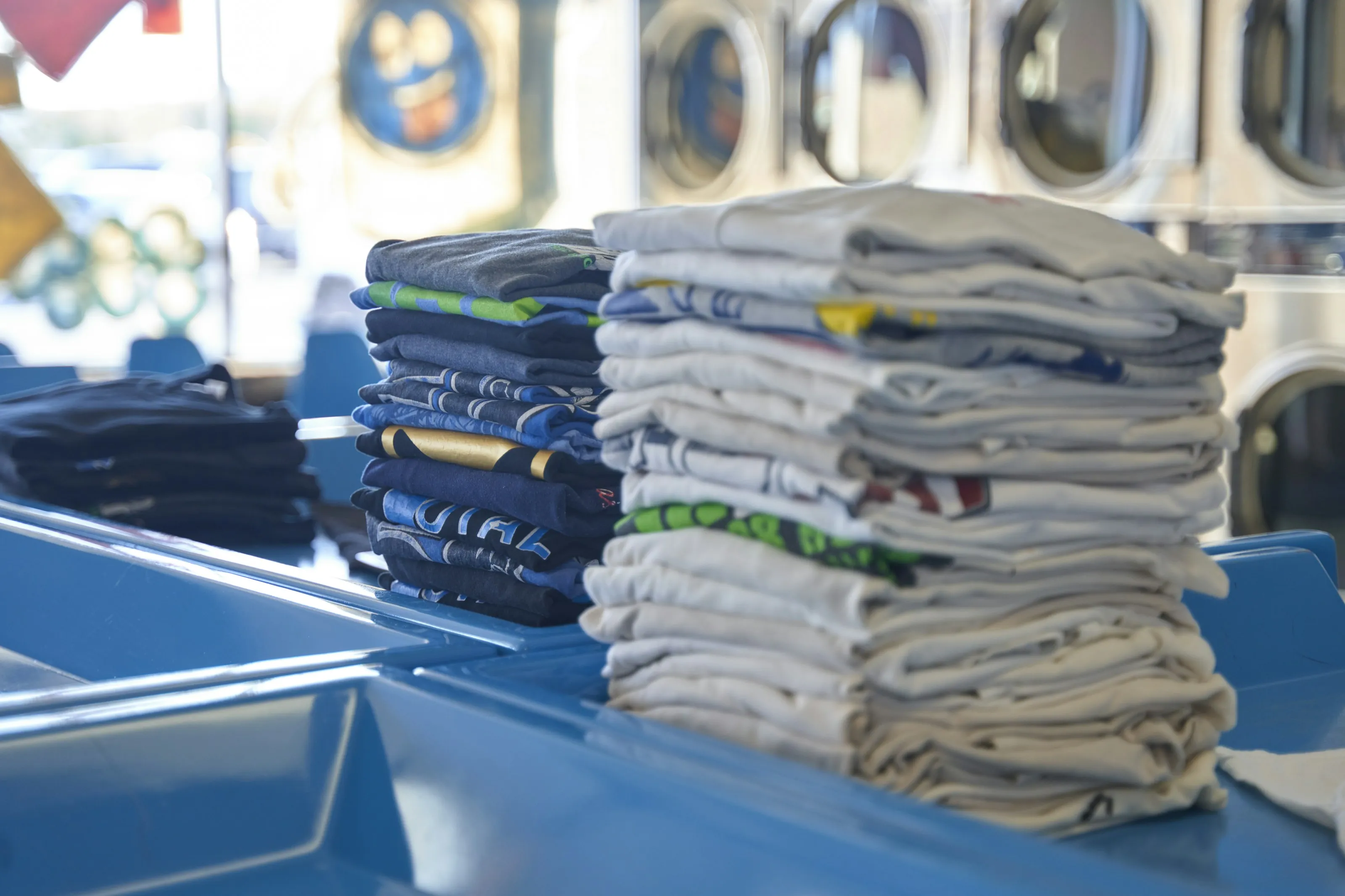 Neatly folded stacks of shirts on a laundromat table
