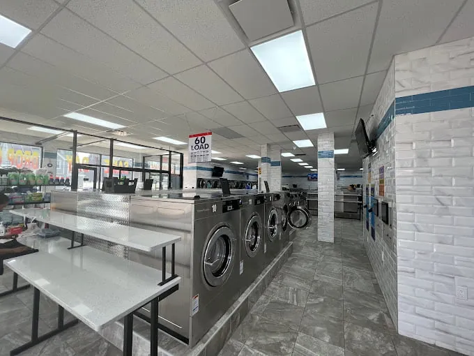 Stainless steel washers and white folding tables inside Farmers Laundromat